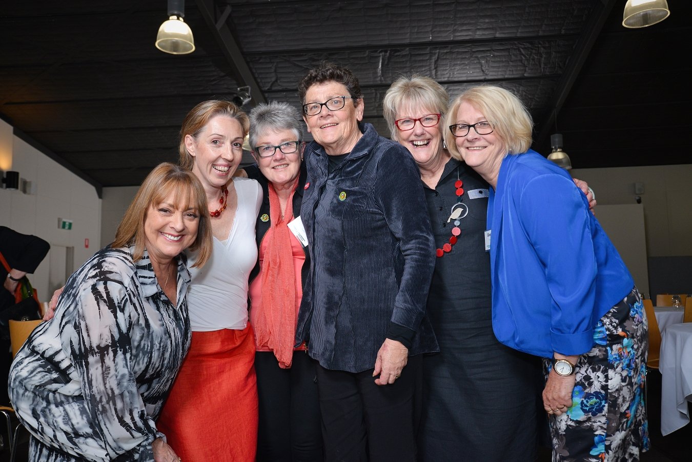 A joyful group of women from the Bigger Hearts community in Ballarat, gathered closely together and smiling at the camera.